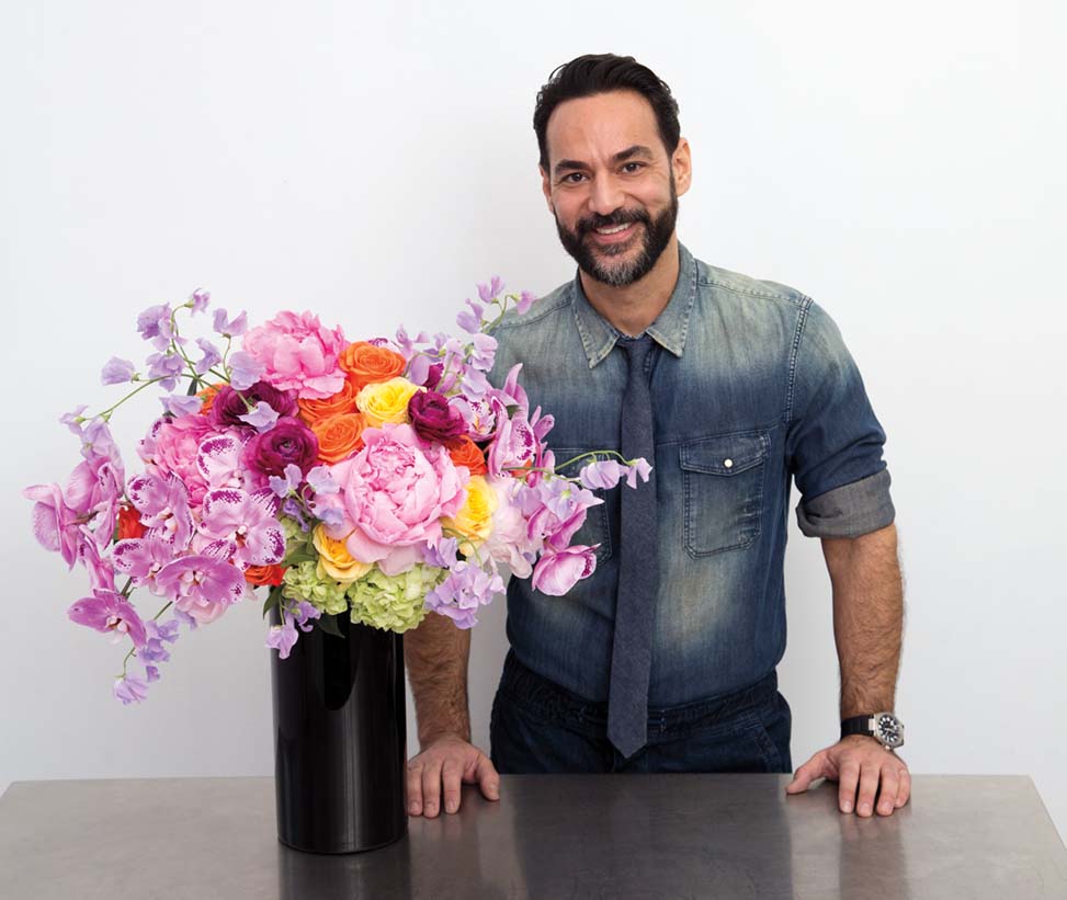 Floral designer Oscar Mora stands beside his finished flower arrangement