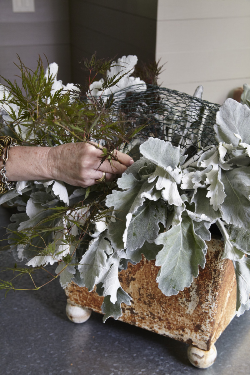 Floral designer adding dusty miller leaves to arrangement
