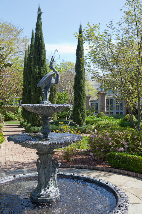 A fountain with a bird statue at the top sits in a garden in Charleston.