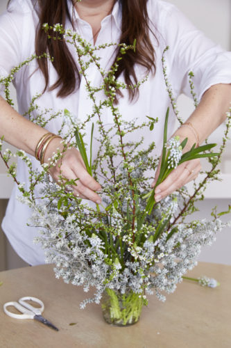 Mimi placing flowers and leaves of white muscari into arrangement