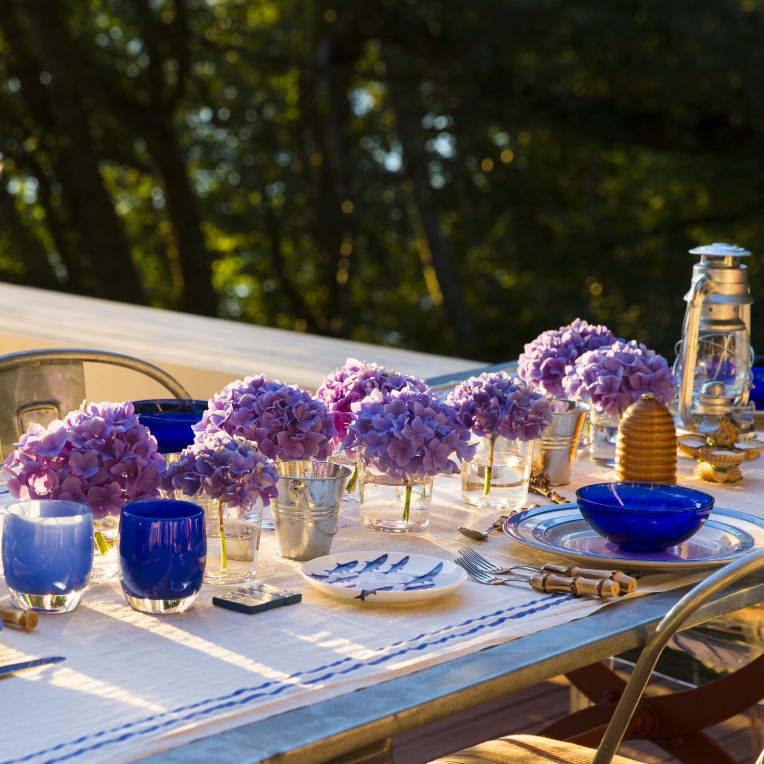 Ted Kennedy Watson set this outdoor table with a mix of cobalt china and glassware, and used single hydrangea blooms in simple glasses.