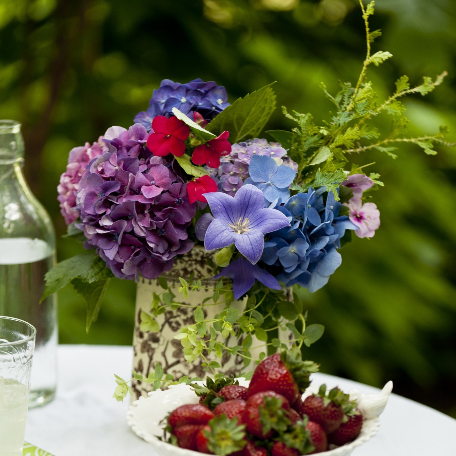 Summery arrangement of pink, purple, and blue hydrangeas with impatiens and a balloon flowers.