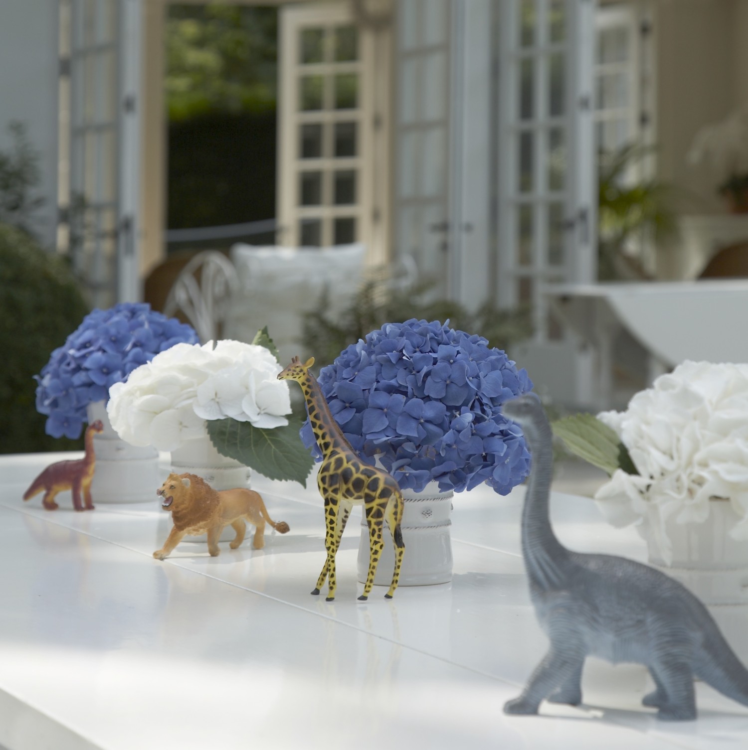 Party table decorated with hydrangeas and dinosaurs and animal figurines.