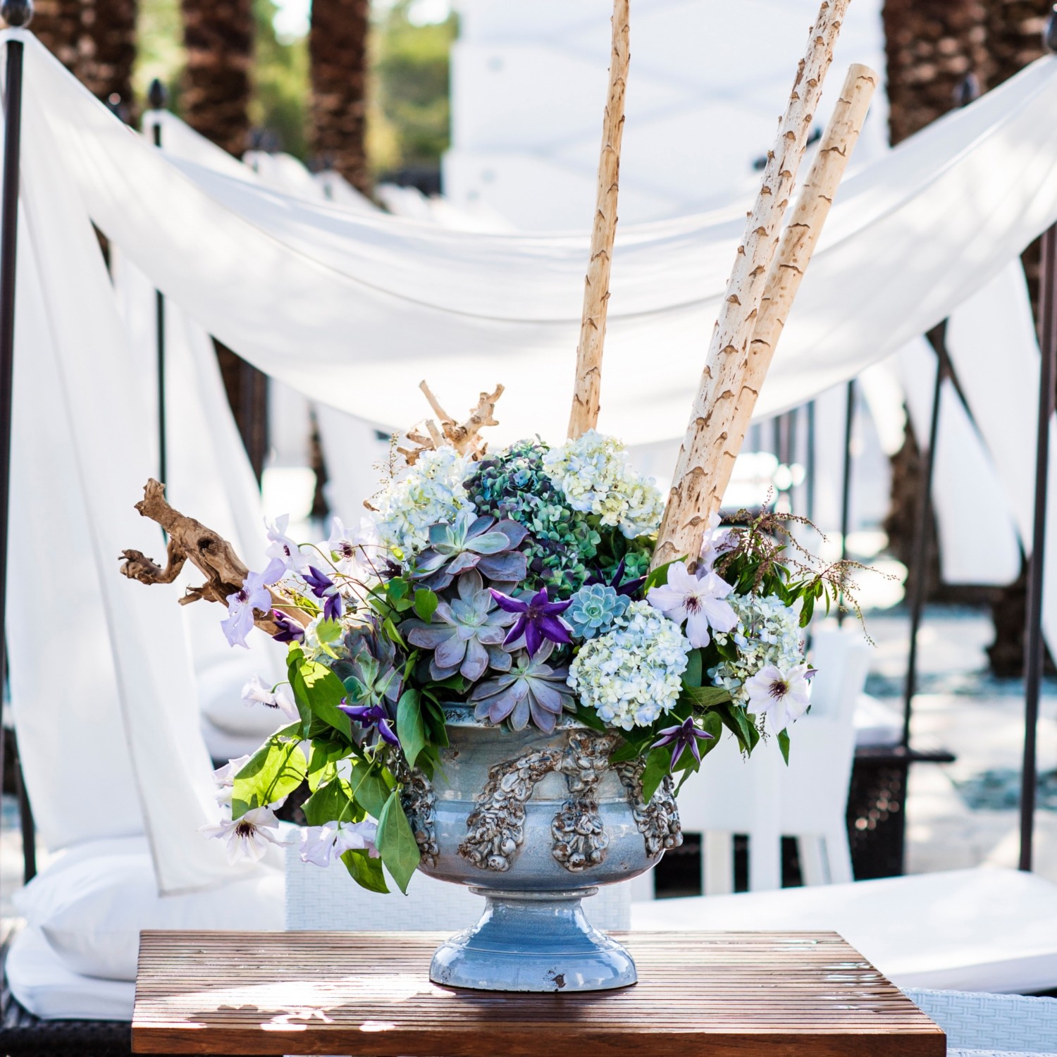 A symphony of blue flowers, complete with batons, is set in a bower of palms and breezy white linen.