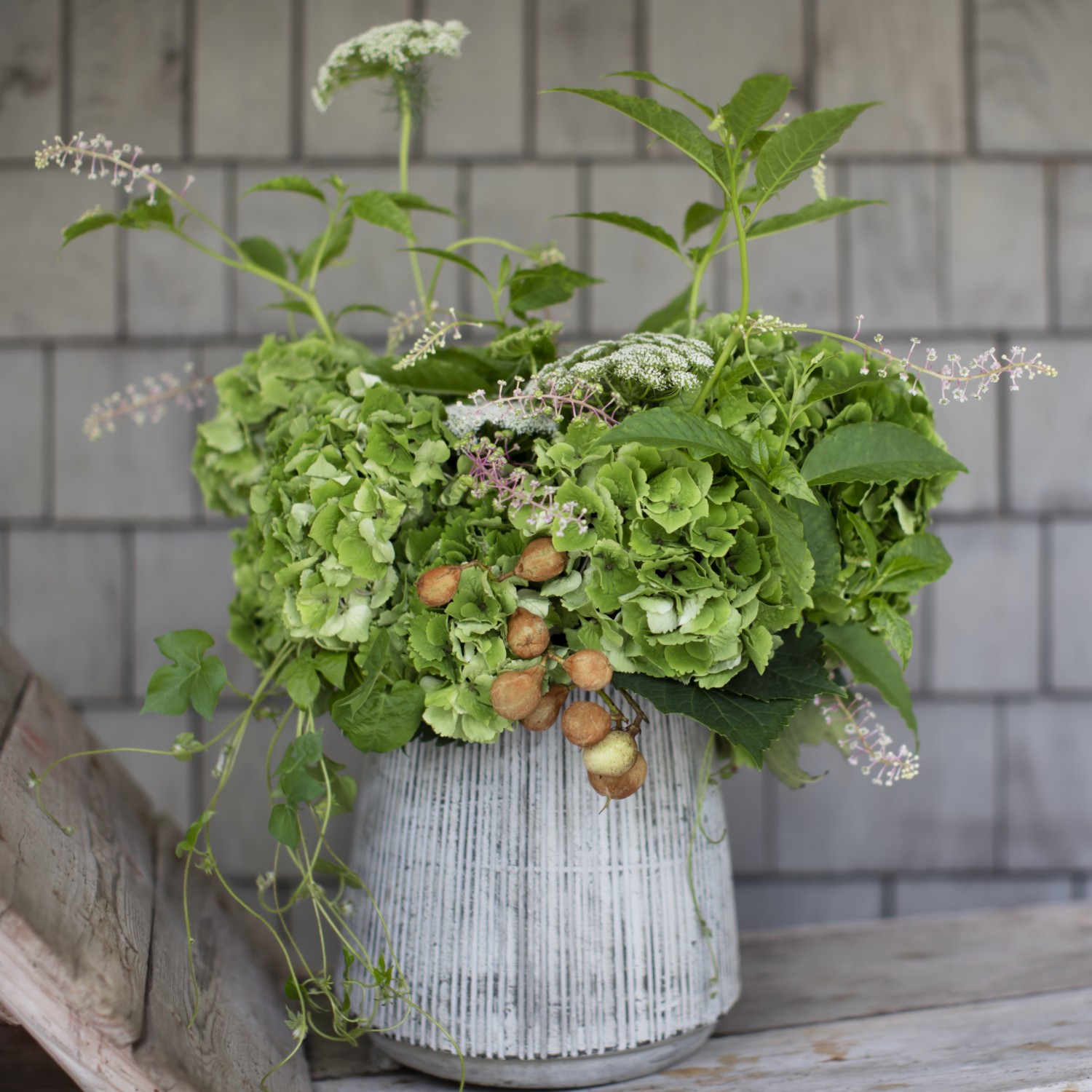 A green arrangement of hydrangeas, wildflowers and berries combine for a fresh cottage-style arrangement. 