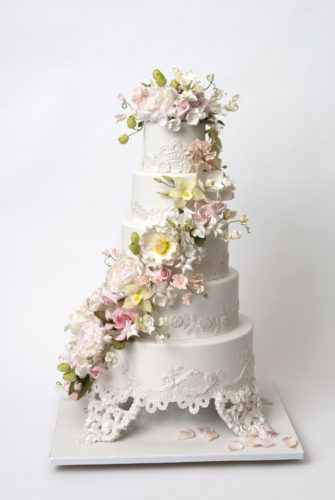 5-tier wedding cake adorned with an elaborate swag of sugar flowers