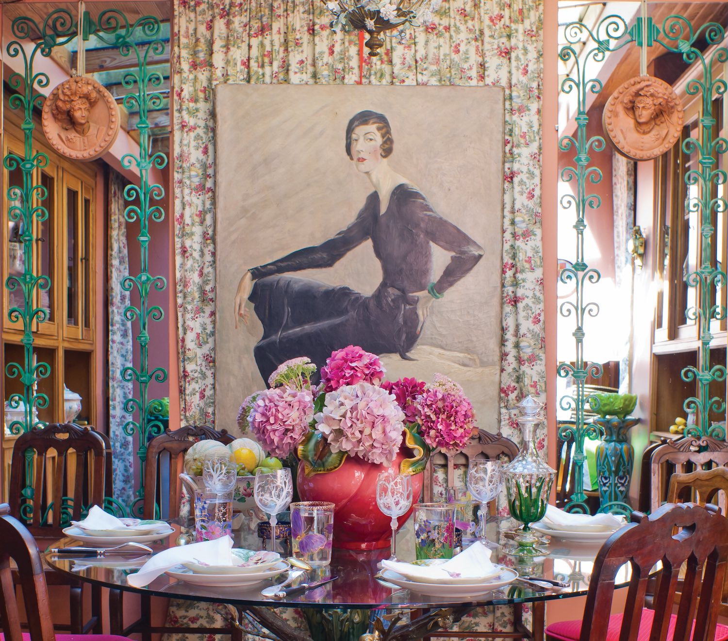 A centerpiece of hydrangeas in shades of pink completes Countess Joy de Rohan Chabot's exuberant dining room table set with her hand-painted glassware. 