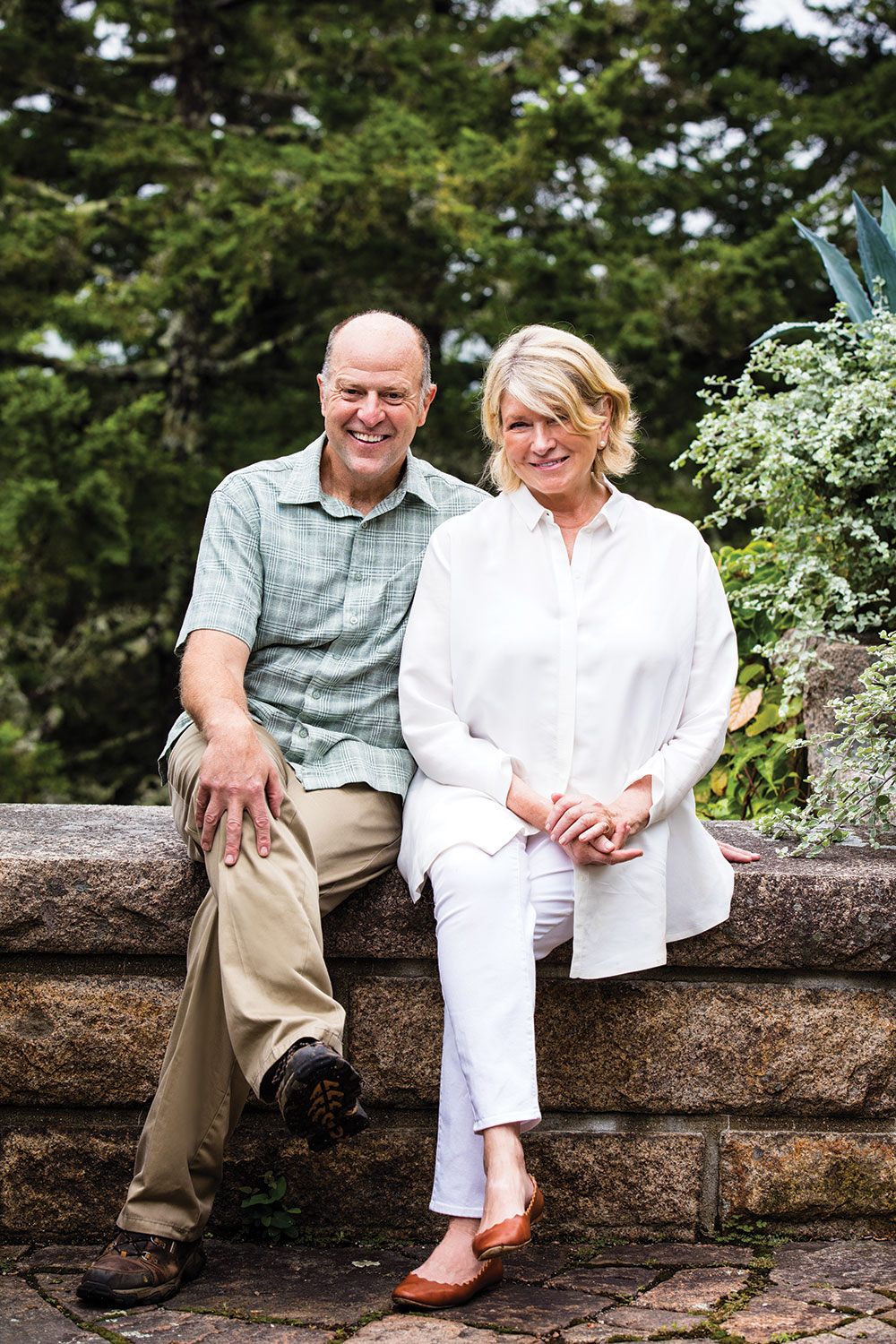 Martha Stewart and writer Daniel Hinkley sit outside on a low stone wall at Skylands, her summer home