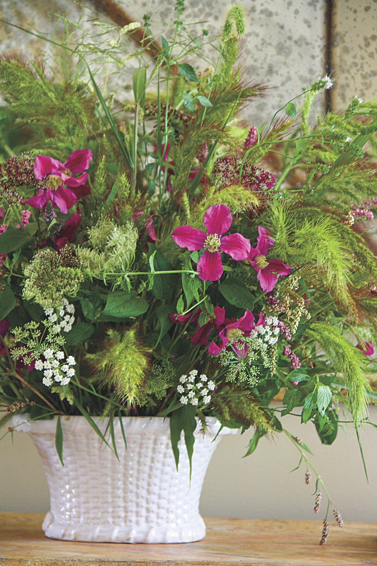 a porcelain basket with clematis, Queen Anne's lace, mint, and wild grasses.