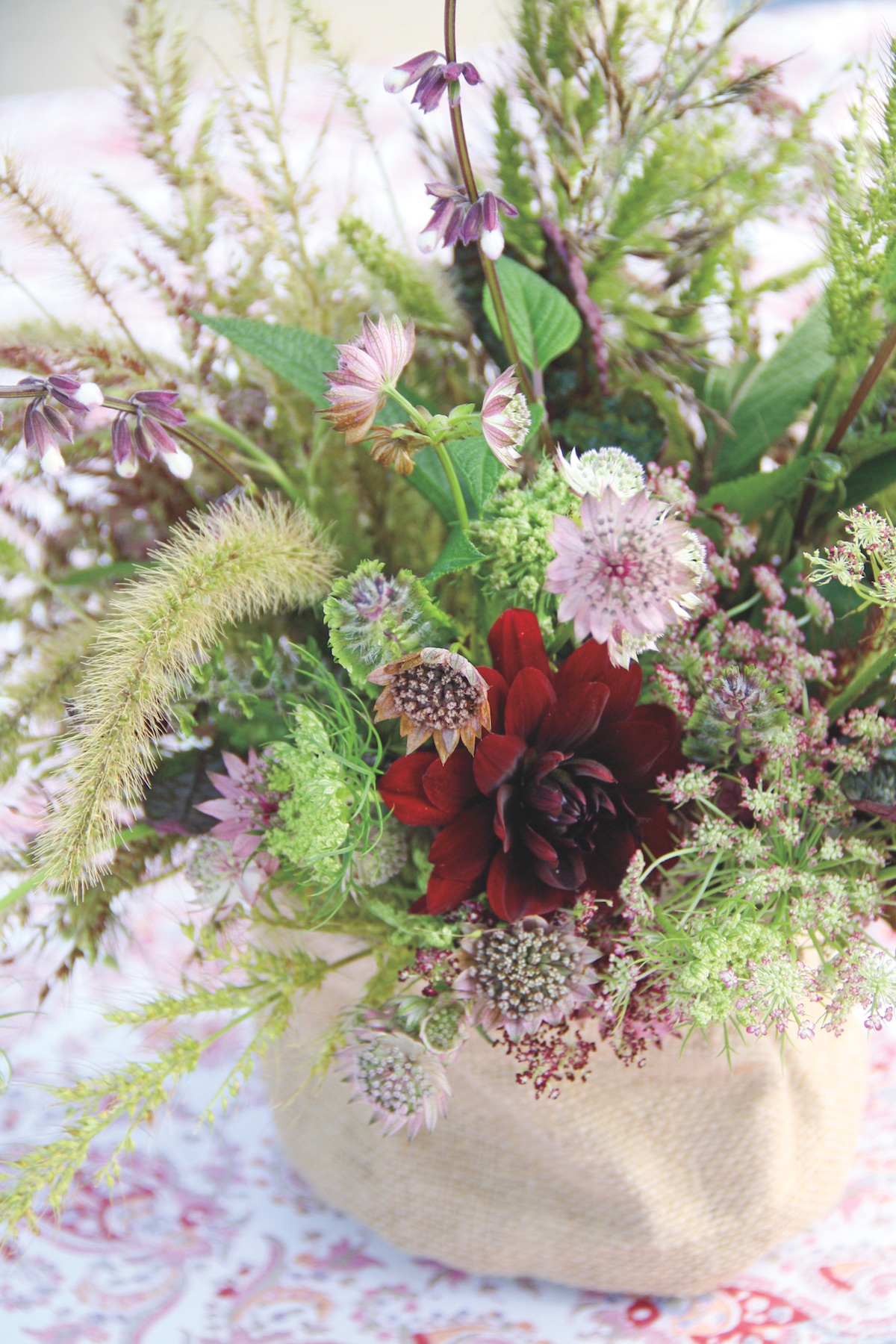 A bouquet of purple and green hues includes wild grasses, dahlias, masterwort, and chocolate Queen Anne’s lace.