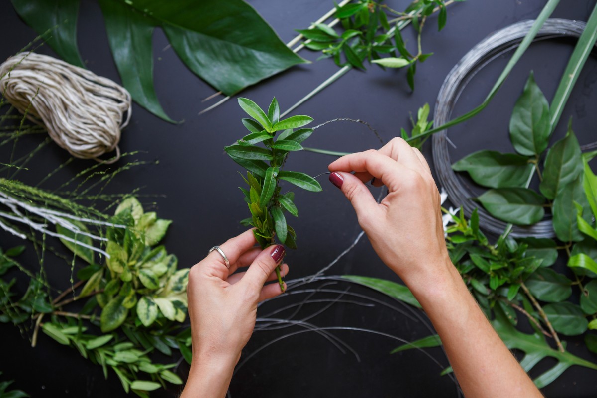 Floral designer using floral wire with greenery for flower arrangements