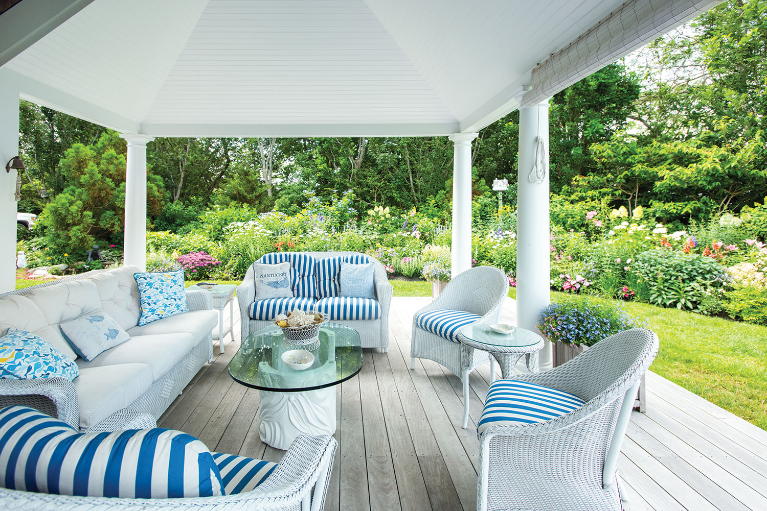 Wicker furniture with blue and white striped cushions on the porch at Bucktucket, at Nantucket home and garden.