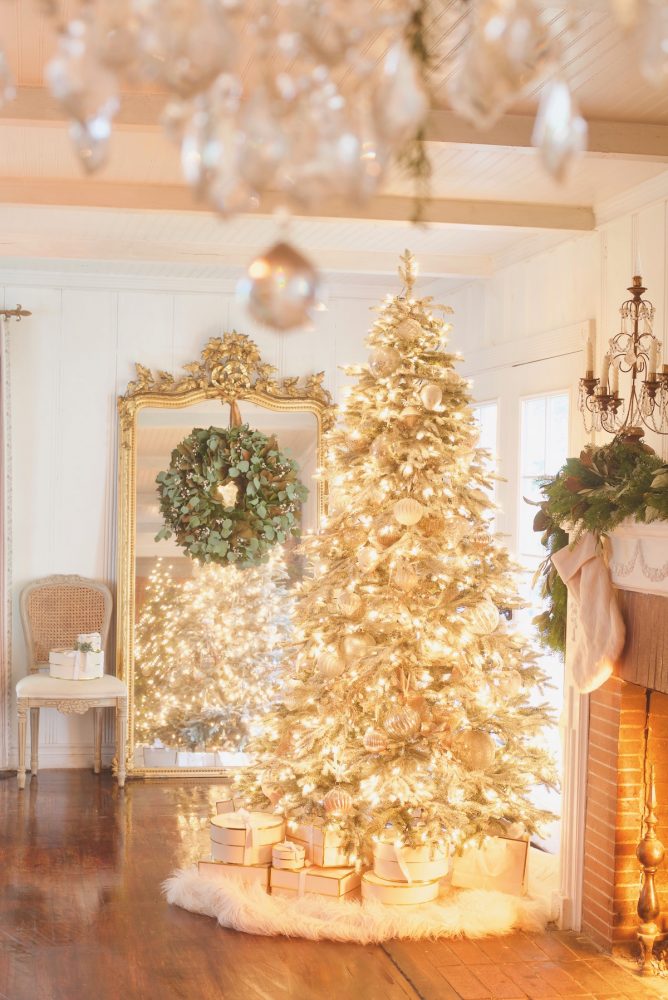 A white lit Christmas tree in a white living room.