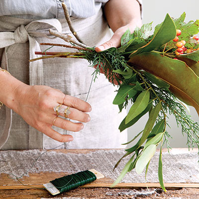 Jessica Sloane wraps twine around a bundle of evergreen branches and berries for her garland