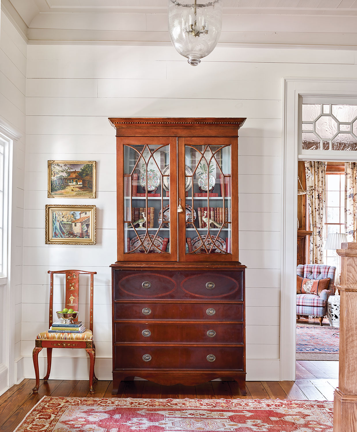 The fretwork design of the antique English secretary blends Edwardian, Queen Anne, and post-Victorian elements, making it a “stylistic mutt” that complements other pieces of varying provenances.