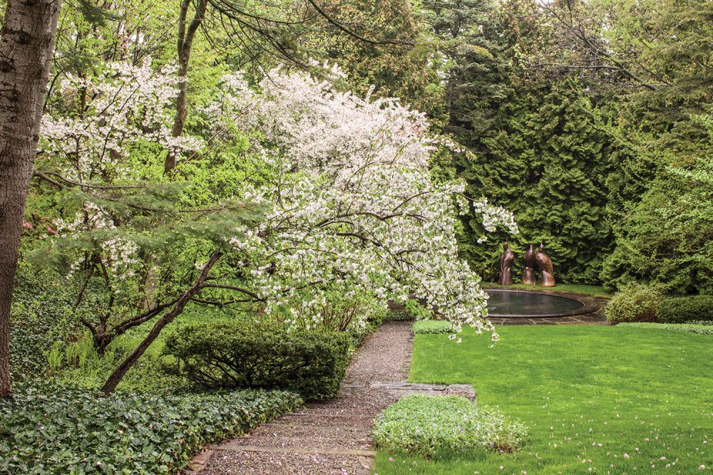 A small white flowering tree bows over a path leading to a pond at Melissa McGrain's estate, which was designed by Fletcher Steele, in Pittsburgh, New York