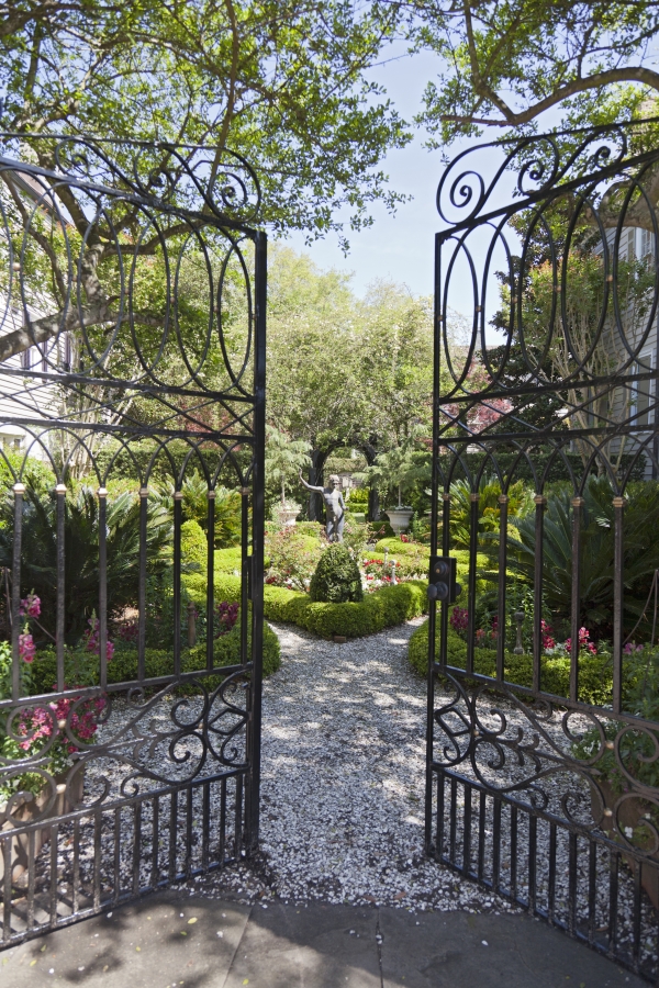 Iron gates open to a garden with an eighteenth century statue.