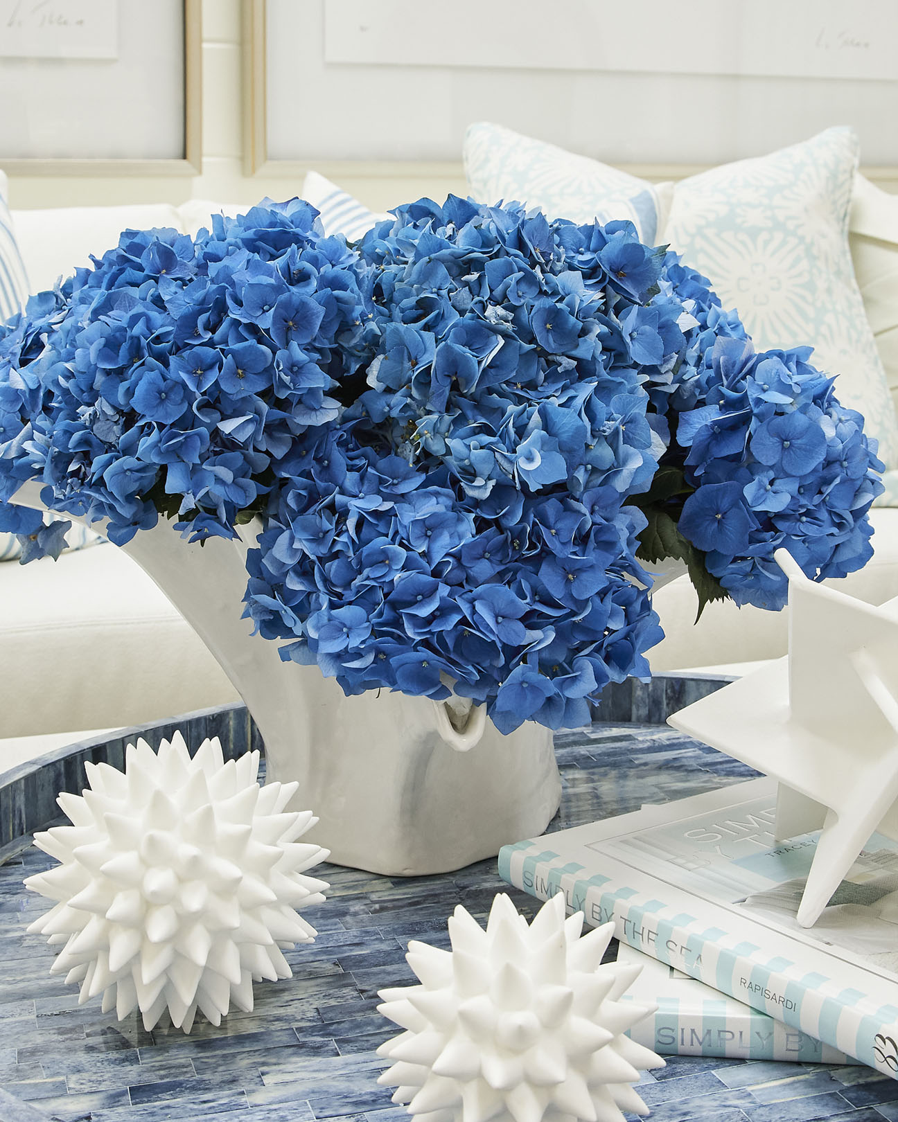 A white ceramic vase with deep blue hydrangeas arranged by Renny & Reed.