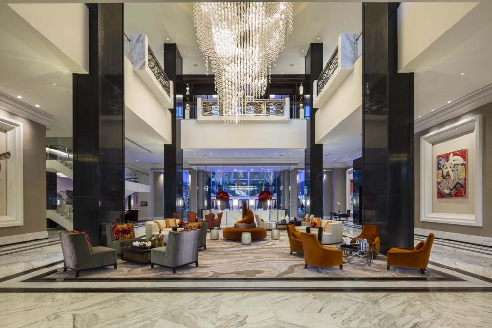 The Post Oak Hotel's two-story lobby features a massive chandelier dripping in crystals. With marble floors, dramatic black accents, and modern art and furniture, the contemporary interior nods to 1920s Art Deco style. 