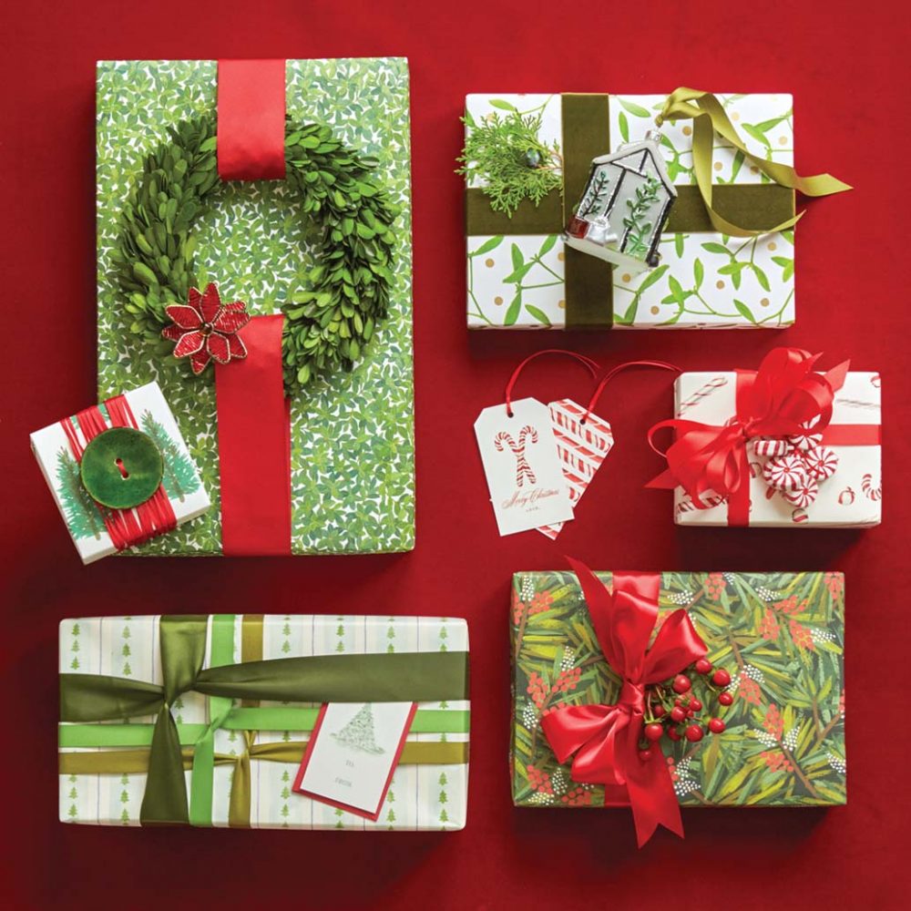 Red and green holiday gift wrap ideas. Adornments include a large green button, a small green wreath, faux red holly berries, faux peppermint candies, a blown glass tree ornament, and a greenery sprig.