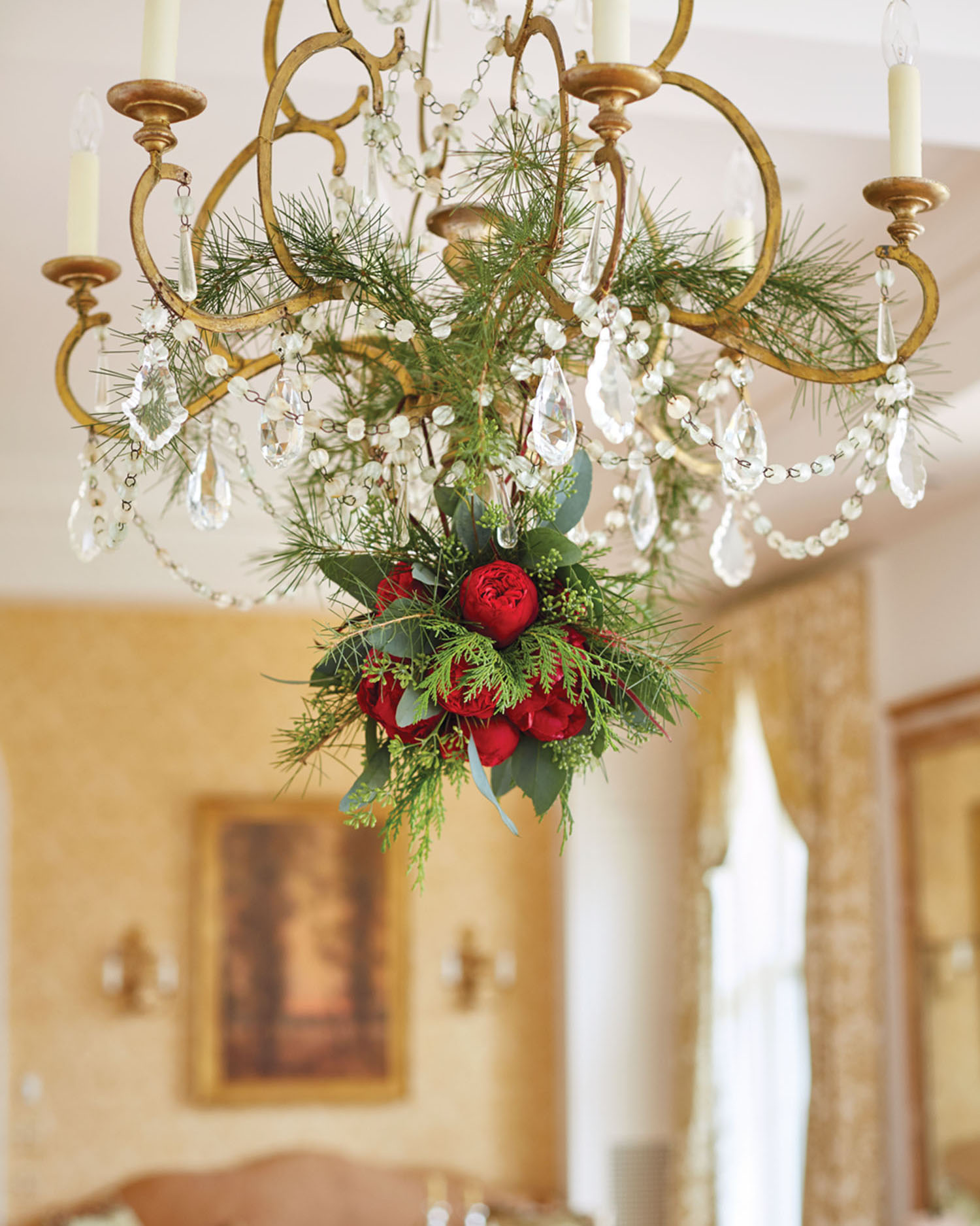 crystal chandelier decorated with evergreen branches and red flowers