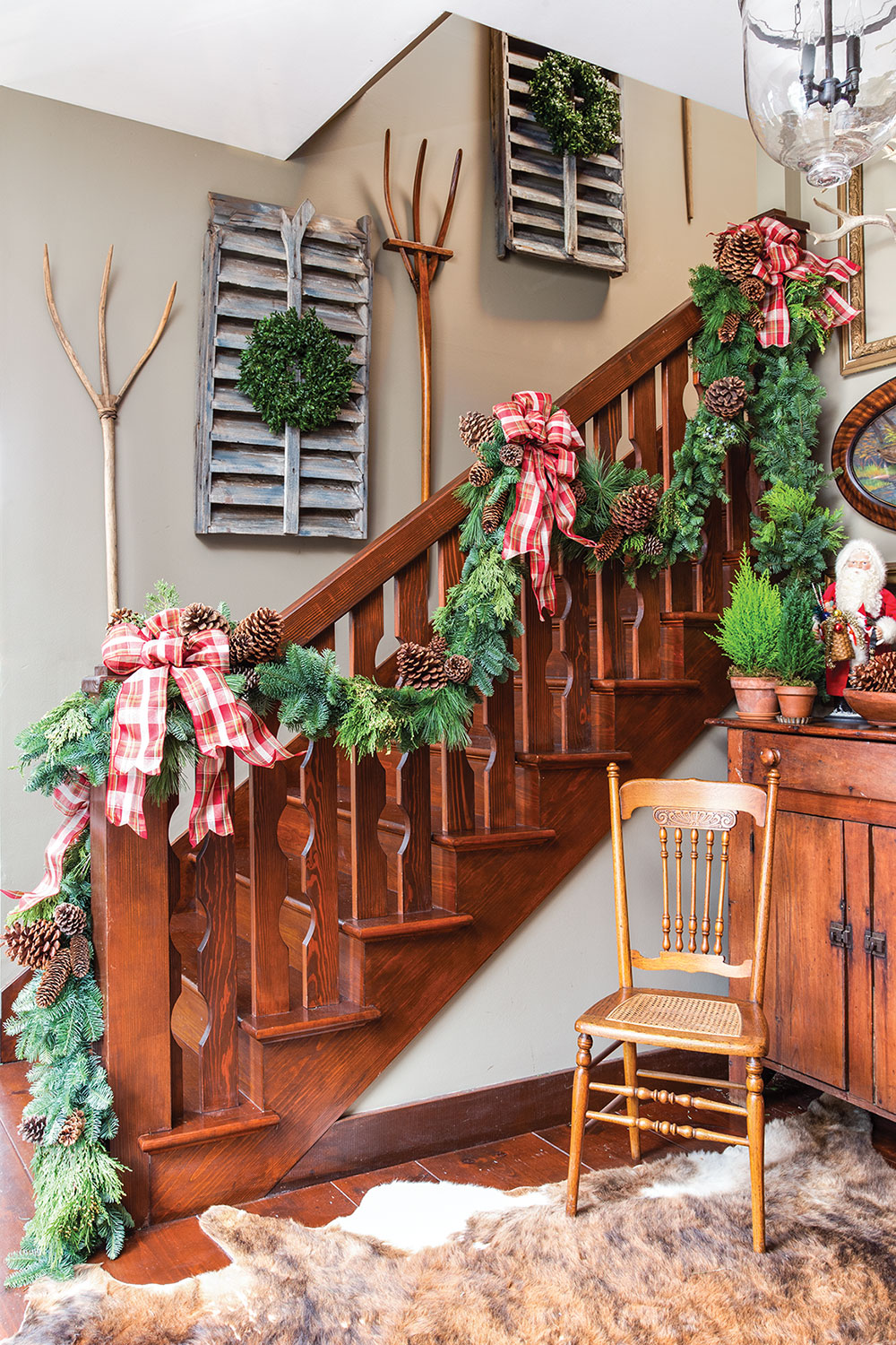 Evergreen Christmas garland with red and white checked bows on staircase. 