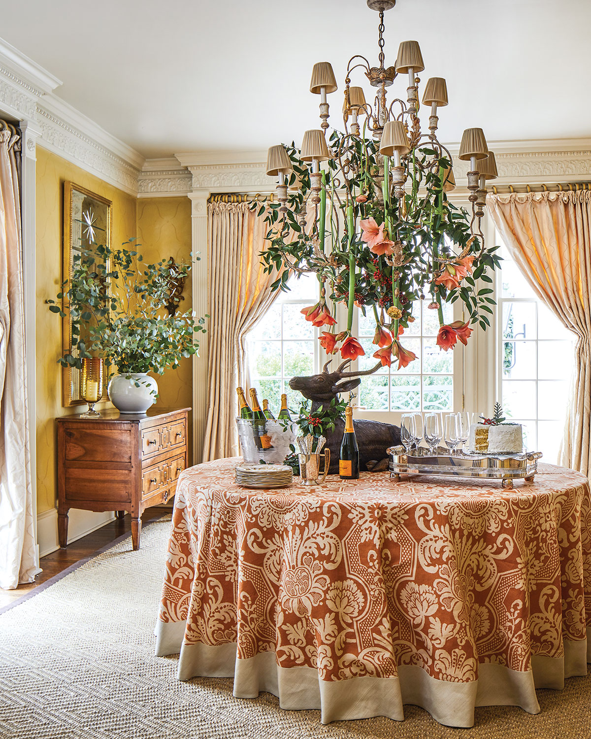 Dining room holiday decor, large arrangement of salmon amaryllis hangs from chandelier.