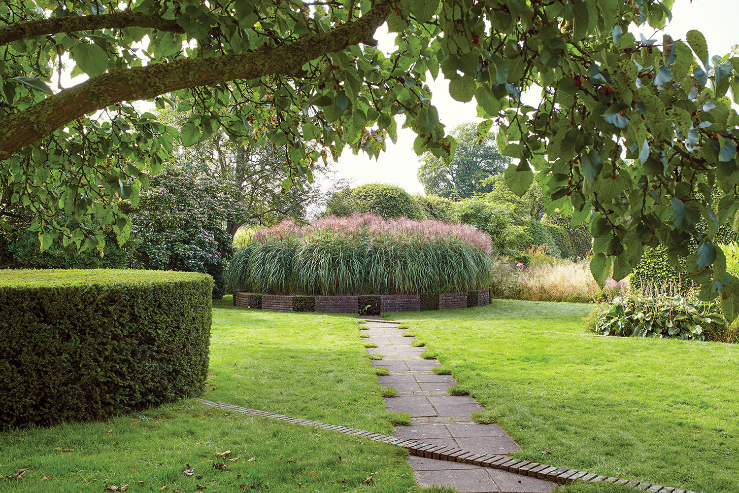 Piet Oudolf gardens; a circular trimmed hedge mirrors a circular planting of tall flowering grass