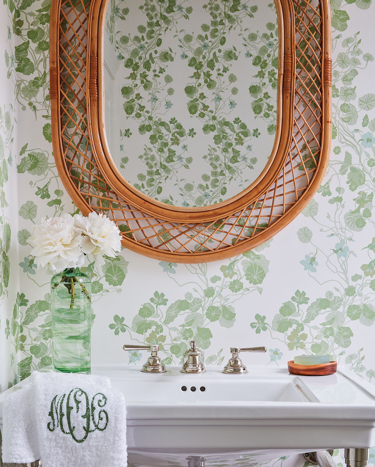 Powder room sink with rattan-framed mirror on Waterhouse wallpaper