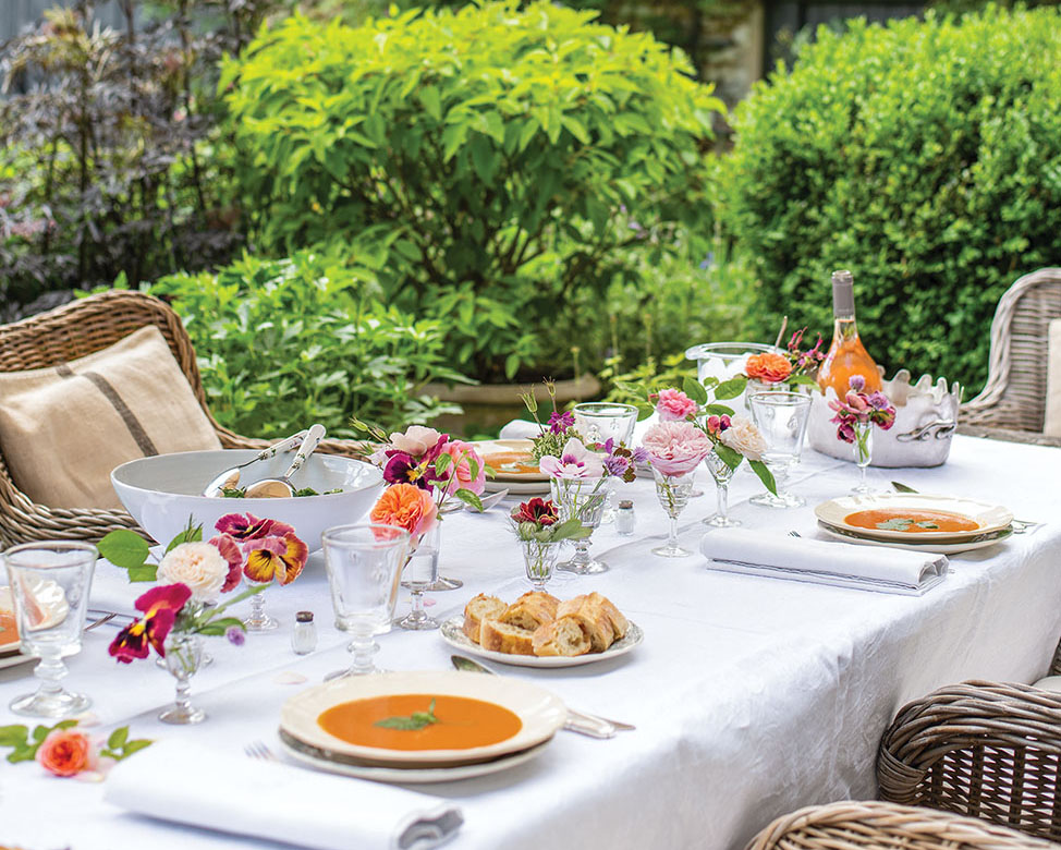 Outdoor dining table set with simple goblets filled with pansies and garden roses