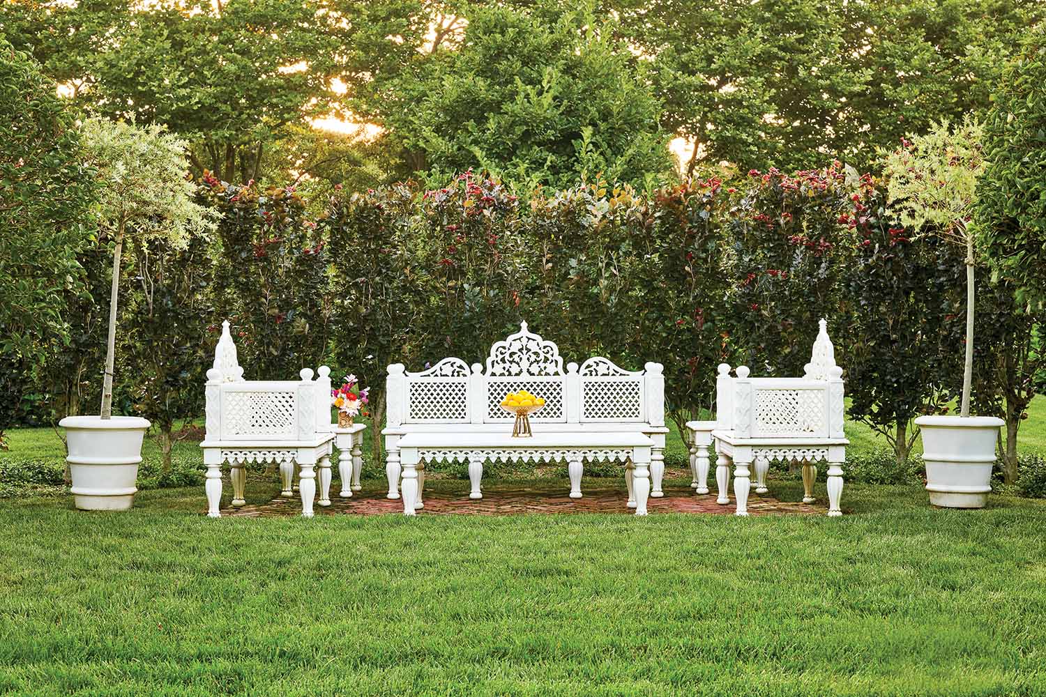 White Indian inspired outdoor furniture sit in a green lawn.