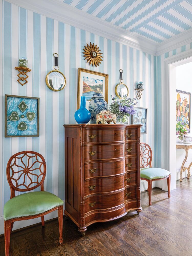 A striped blue wallpaper compliments a wooden antique in the home's hallway.