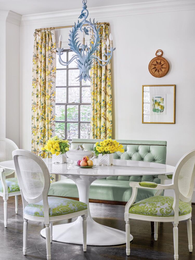 A bright green banquette is matched with white and green chairs in a cheery white kitchen.