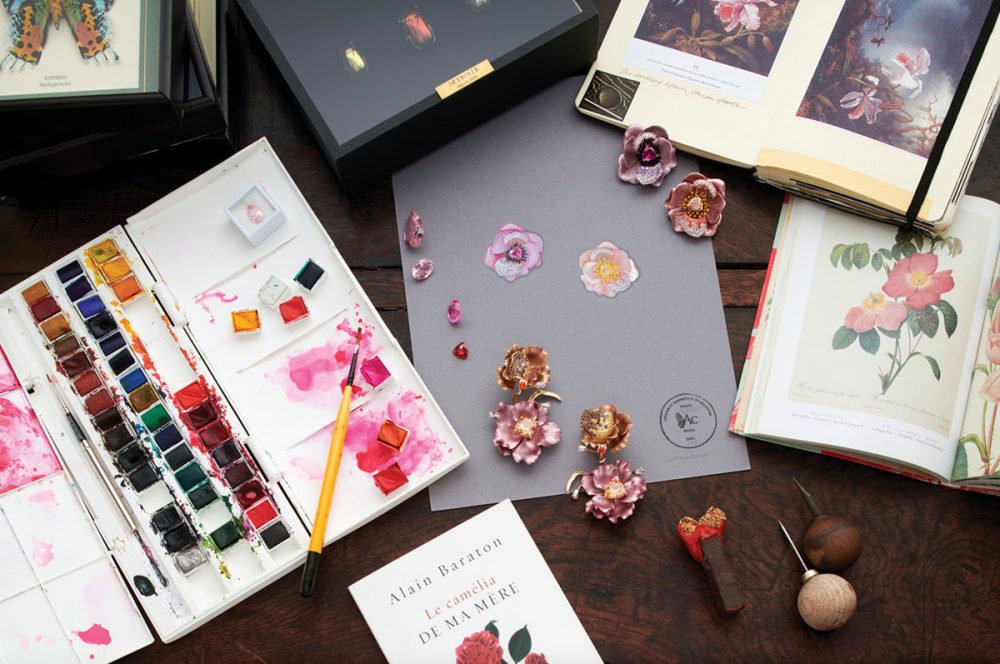 earrings by Anabela Chan on a desk with inspirational books, paints, and paintbrushes