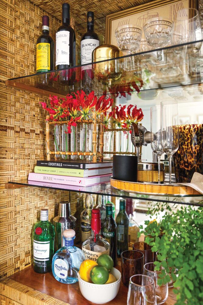 A vintage bamboo china cabinet doubles as a bar. Gloriosa lilies fill a bamboo bud vase from Mecox Gardens.
