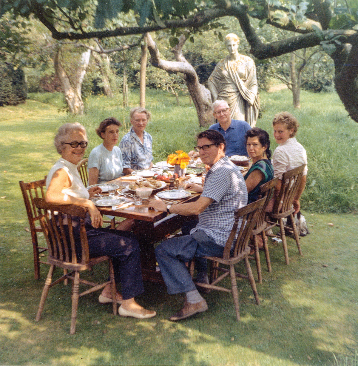 Lee Miller and friends seated at outdoor table in her Farleys House garden (circa 1960).