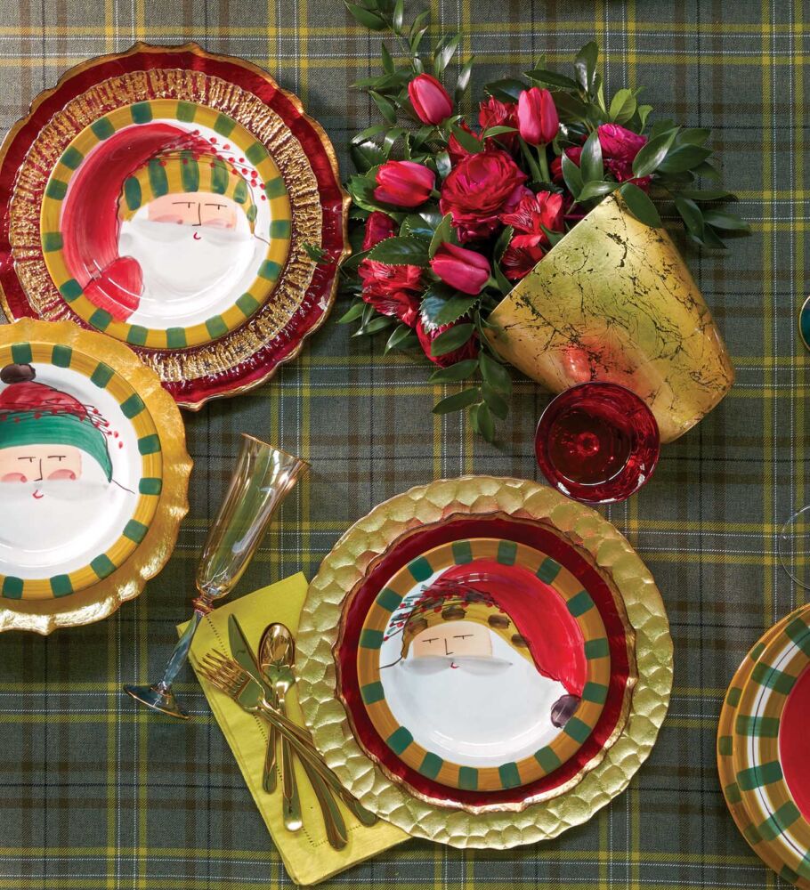 Christmas table setting with Santa Claus plates on a plaid tablecloth.