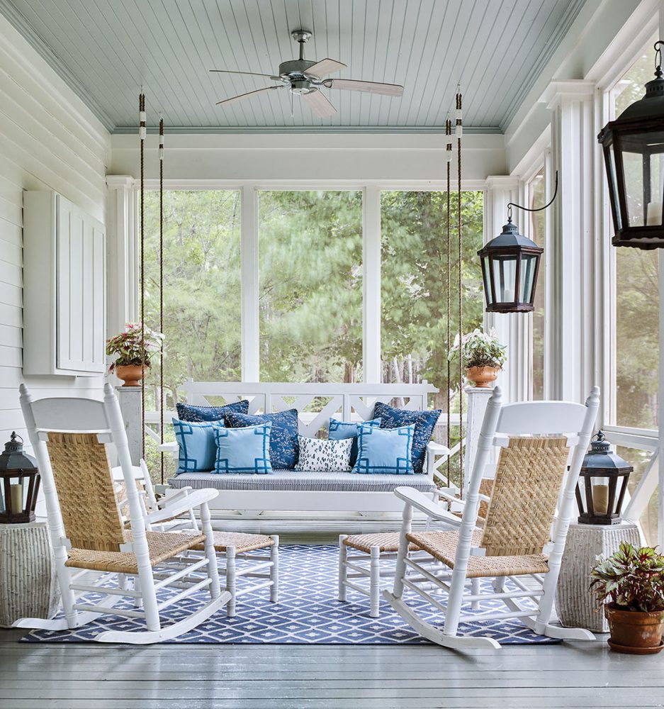 Photo the screened porch at McCurdy Plantation. Designer James Farmer chose a gray floor and light blue ceiling, and furnished it with two rocking chairs and a bed swing covered in blue pillows.