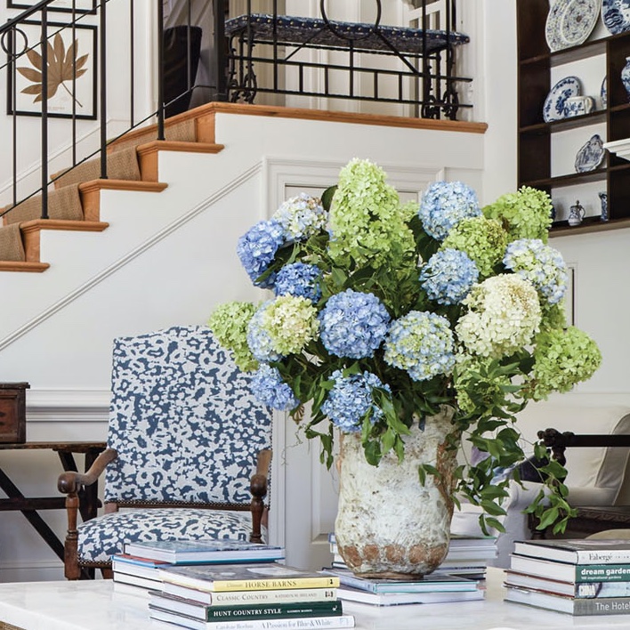 Large, blue, green and white hydrangea arrangement on low table in foyer.