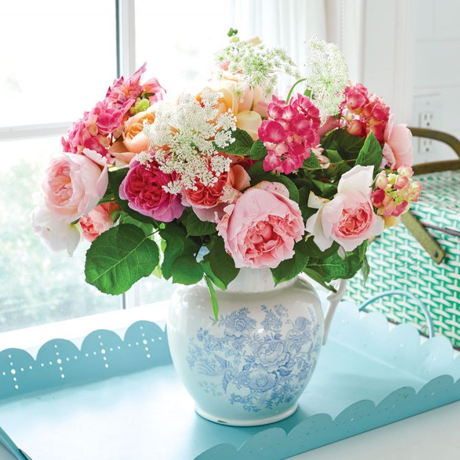 Pink and peach flower arrangement in blue and white pitcher
