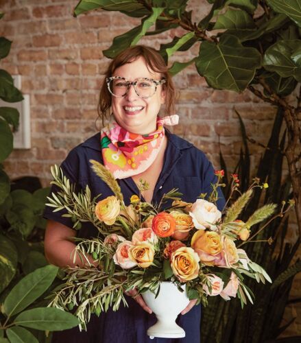 Florist proudly holds her Tuscan inspired floral arrangement.