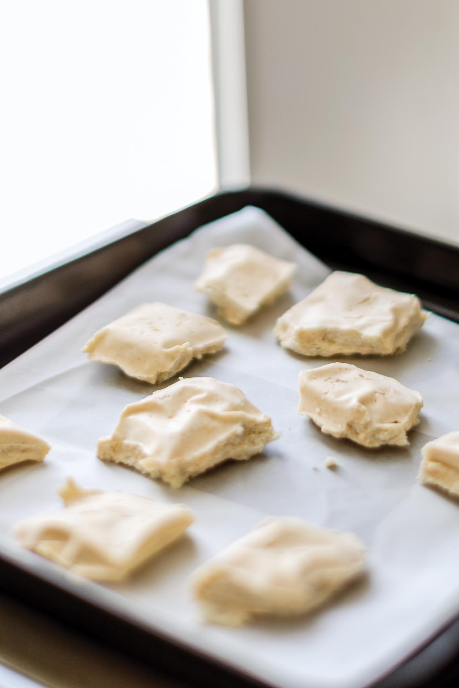 A baking sheet holds squares of raw dough.