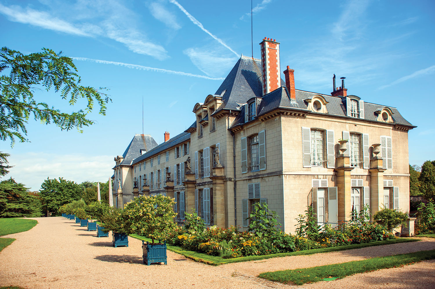 Chateau Malmaison stands tall with pale blue window shutters and orange trees lining its front.