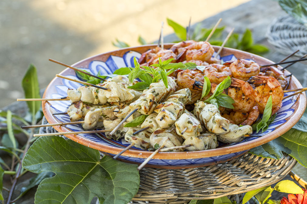Platter filled with Chicken and Shrimp Kebabs, garnished with fresh basil