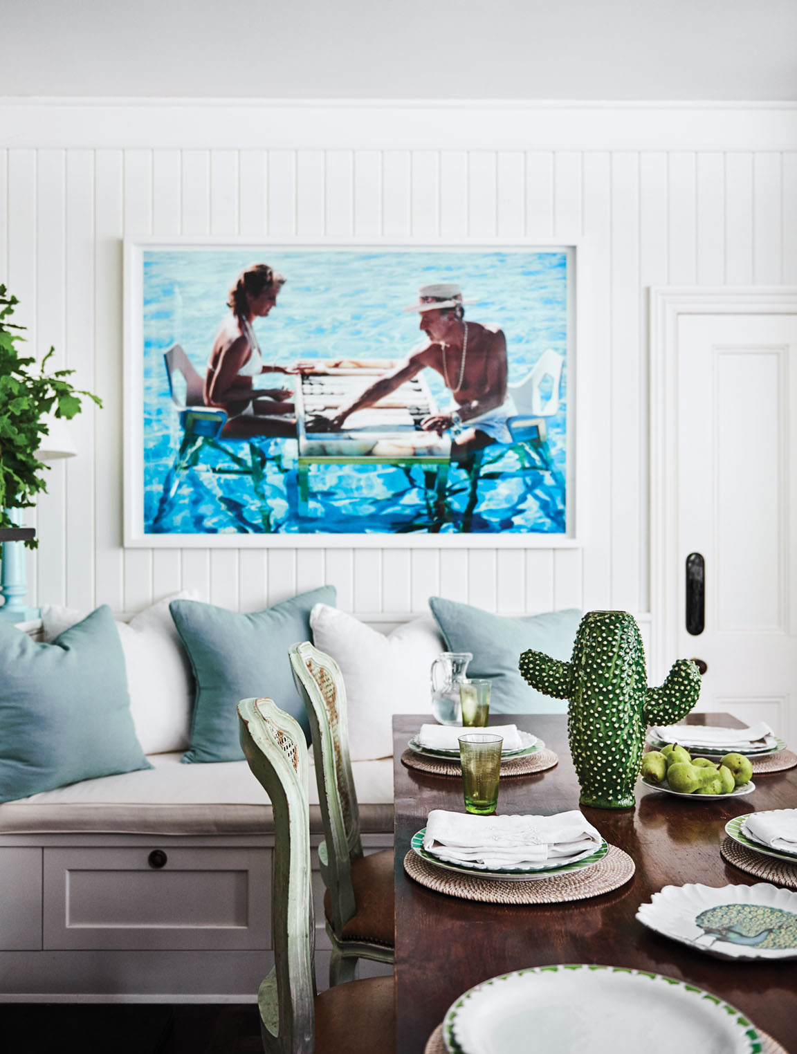 Above a banquette, the Slim Aarons' photograph features couple playing a board game in a pool