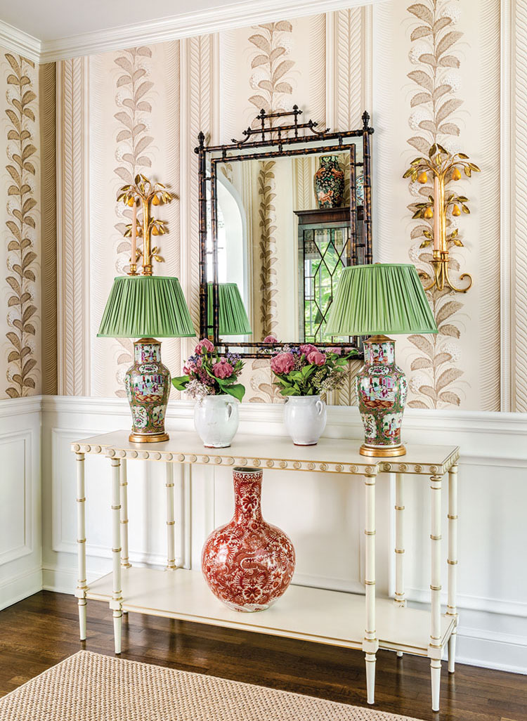 Entryway of Connecticut home with console table, pair of green shaded lamps flanking Chinoiserie mirror.