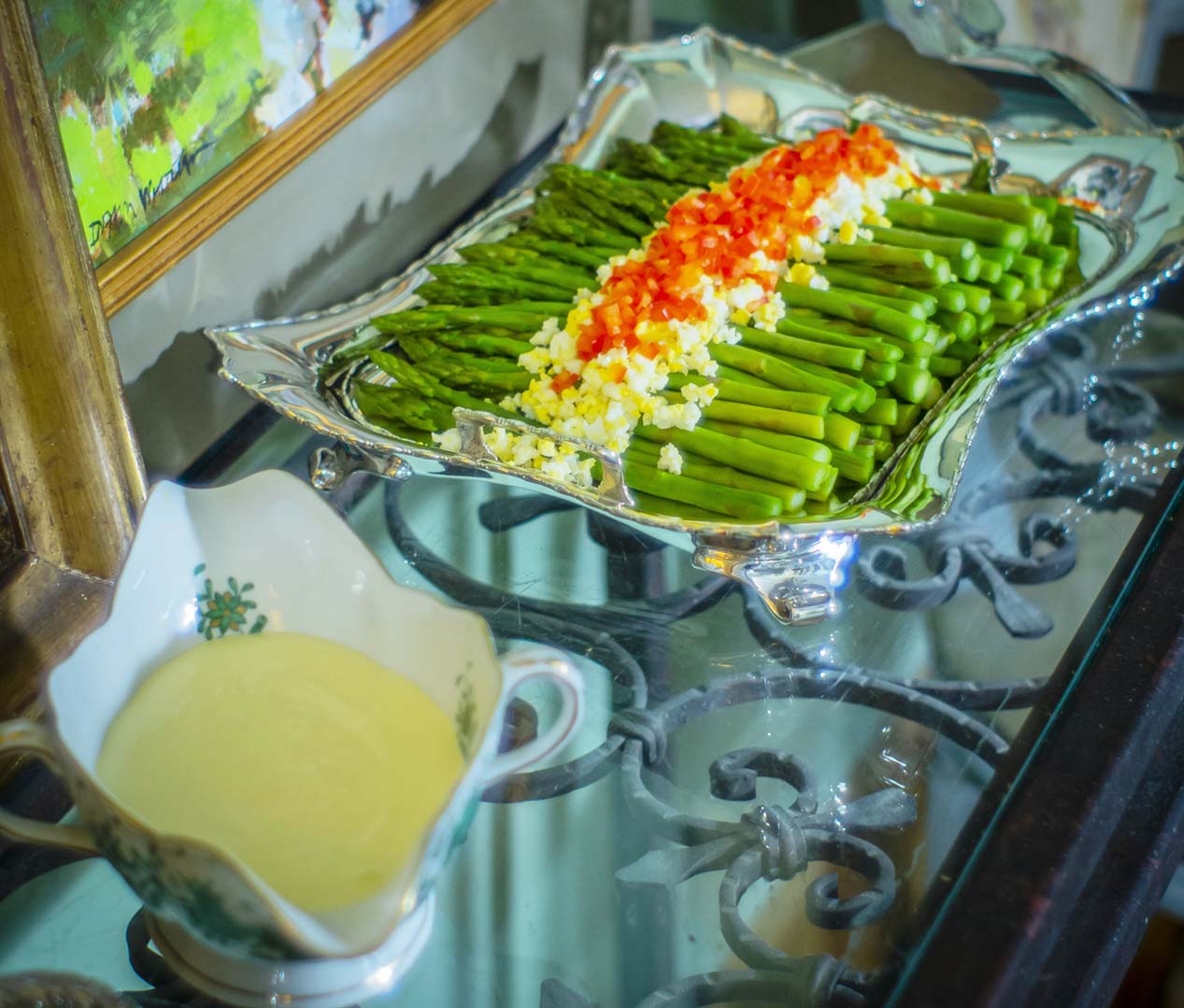 Steamed asparagus in a Sterling Asparagus Tray by Tiffany & Co, with a side of hollandaise sauce in a Herend “Indian Basket” Green gravy boat, both from Replacements Ltd