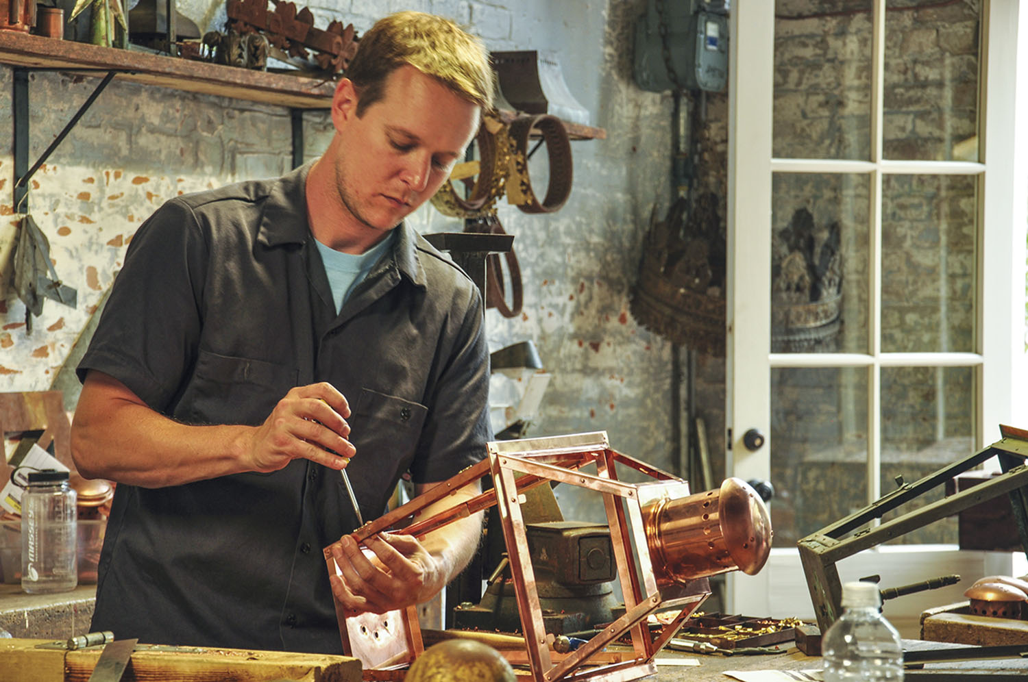 a craftsman at Bevolo works on a copper gas lantern