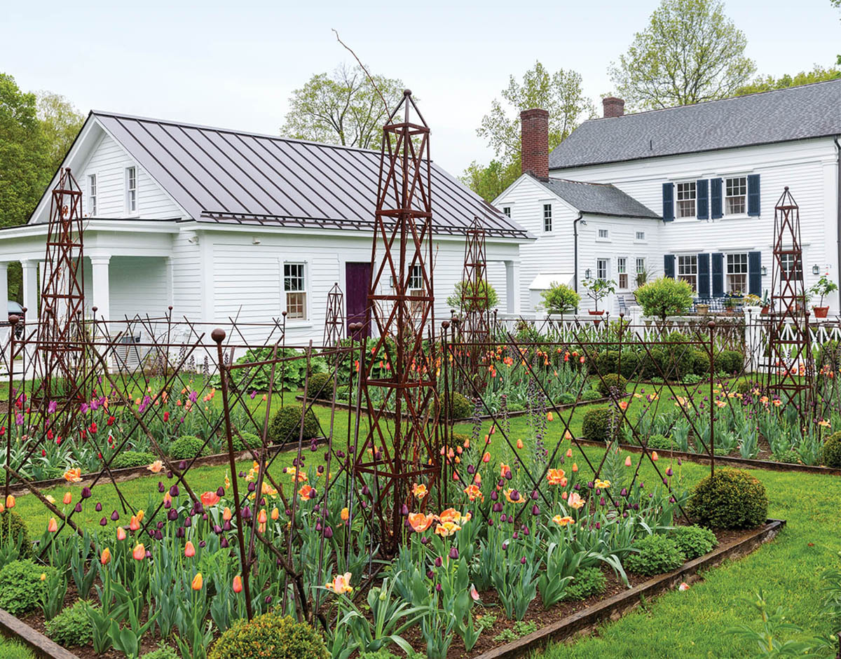 White farmhouse and rustic garden parterres blooming with tulips at his Millbrook country home, from the pages of his book "A Year at Clove Brook Farm" (Rizzoli)