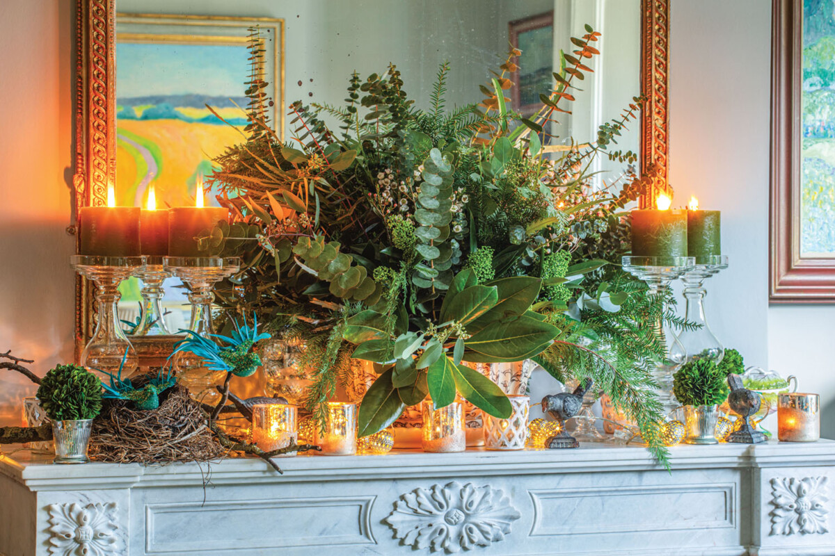 The mantel, full of greenery, candles, and natural materials, has a rustic charm.